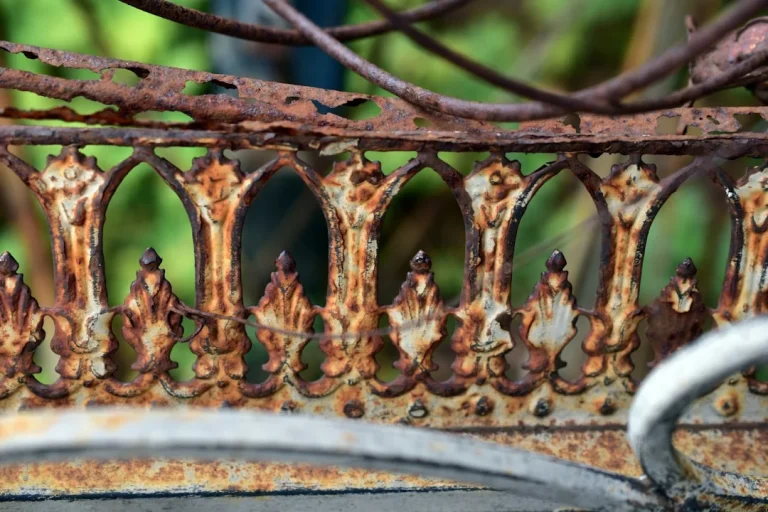 A rusted metal fence with a bird perched on top of it