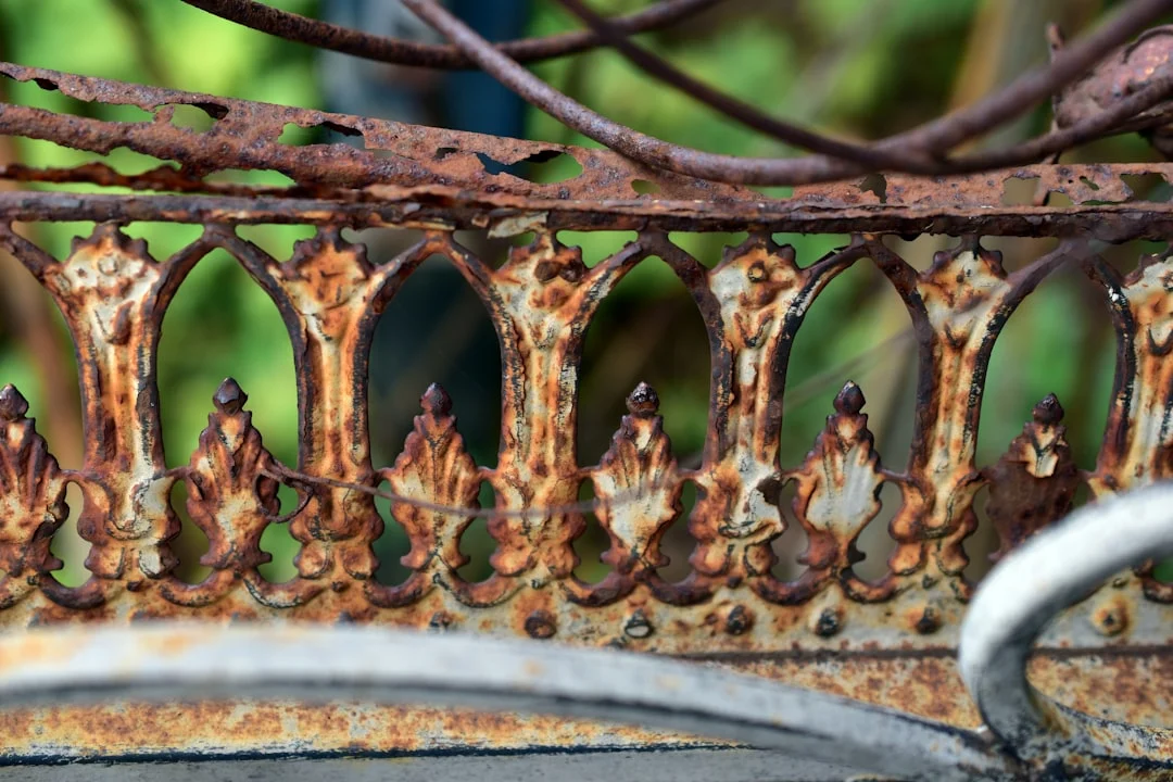 A rusted metal fence with a bird perched on top of it